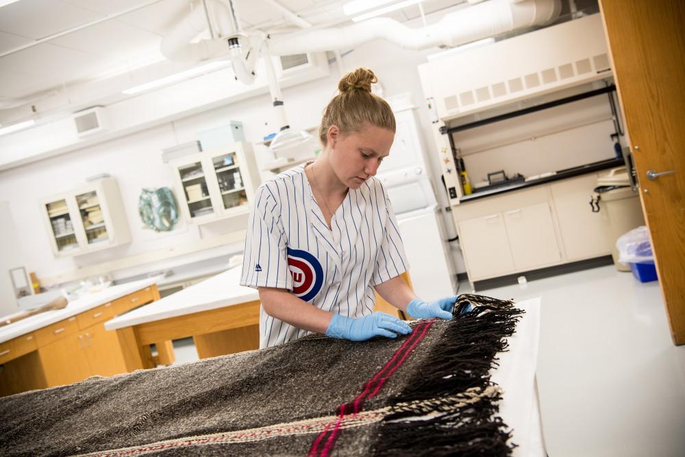 A Beloit student studies a textile from the collection in the 洛根人类学博物馆.